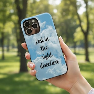 Puede incluir: Funda de teléfono azul claro con diseño de nubes y el texto "Lost in the right direction" en escritura negra. La funda tiene un borde negro y un recorte para la cámara.