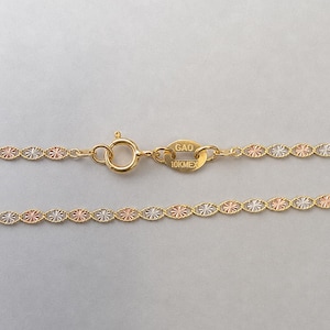 Puede incluir: Primer plano de un collar de oro con una cadena delicada. La cadena presenta un patr&oacute;n repetido de peque&ntilde;os eslabones ovalados en oro, oro rosa y plata. El cierre es visible y la etiqueta dice "GAO 10K MEX".