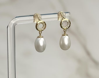 May include: A pair of gold earrings with a small circle of clear stones and a white pearl dangling from each.