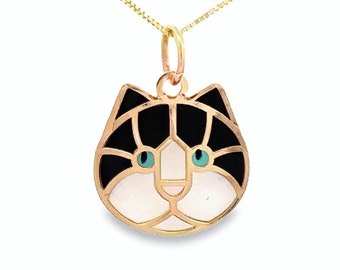 May include: Gold necklace with a black and white cat pendant. The cat's eyes are blue and the pendant has a detailed design.