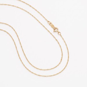 May include: A delicate gold chain necklace featuring a twisted rope link design. The necklace includes a secure spring ring clasp mechanism that connects the two ends of the chain, allowing for easy fastening and removal around the neck area.