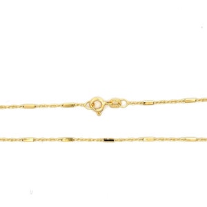 Puede incluir: Un collar de cadena de oro que presenta una serie de peque&ntilde;as cuentas cil&iacute;ndricas pulidas espaciadas uniformemente a lo largo de una delicada cadena de eslabones trenzados. Incluye un cierre de resorte circular y una peque&ntilde;a etiqueta rectangular.