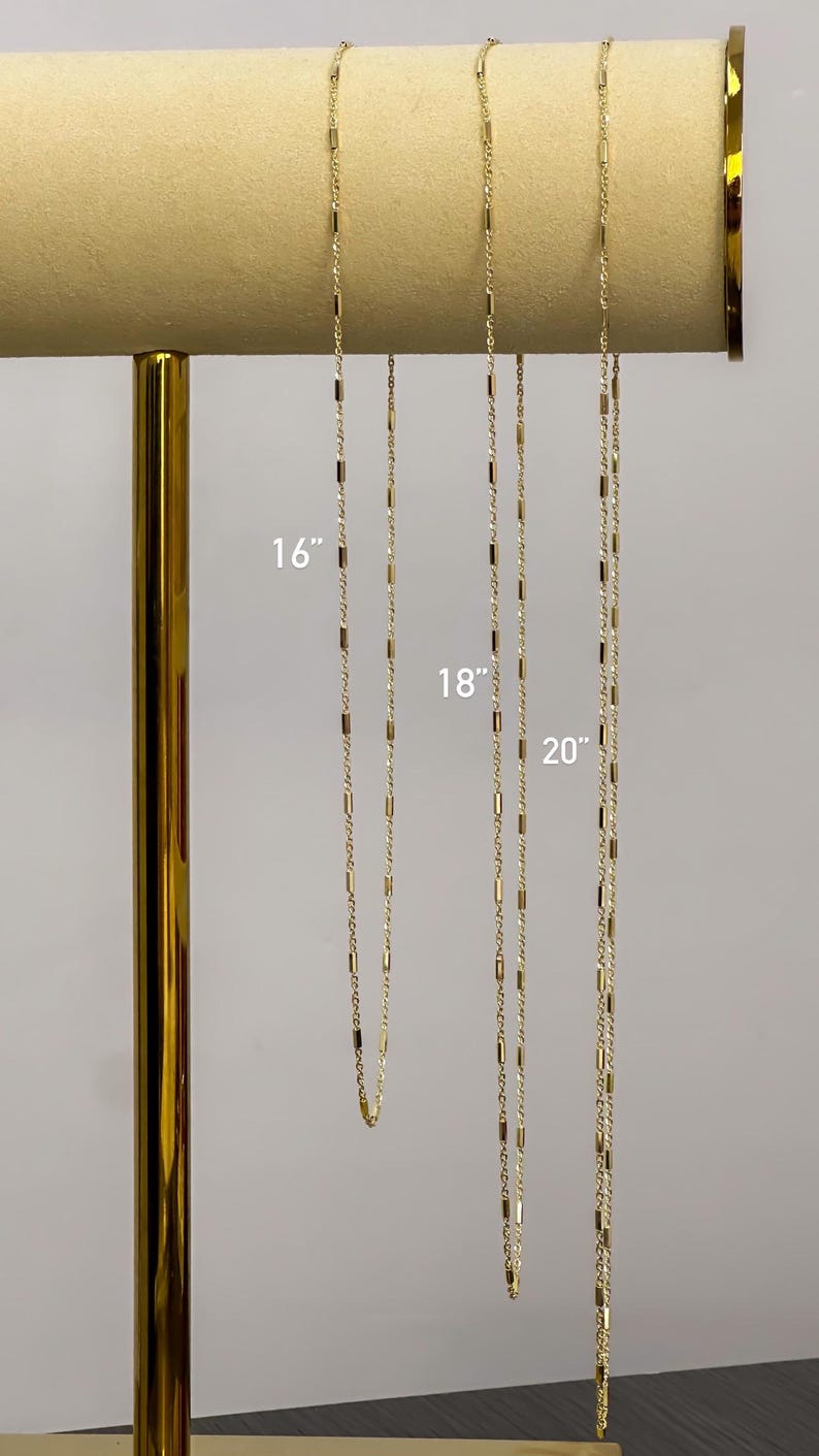 Puede incluir: Tres cadenas de tono dorado con peque&ntilde;os eslabones cil&iacute;ndricos espaciados uniformemente. Las cadenas se muestran en longitudes de 16, 18 y 20 pulgadas, con las medidas correspondientes claramente impresas junto a cada cadena individual.