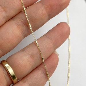 Puede incluir: Un delicado collar de cadena de oro que presenta una serie de peque&ntilde;os eslabones cil&iacute;ndricos texturizados intercalados a lo largo de una fina cadena de eslabones pulidos. El metal tiene un acabado en oro amarillo brillante.