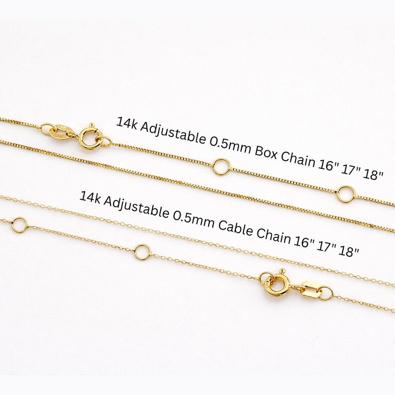 May include: Two gold-colored necklaces with clasps and adjustable chain lengths. The text reads "14k Adjustable 0.5mm Box Chain 16" 17" 18"" and "14k Adjustable 0.5mm Cable Chain 16" 17" 18"". The chains are displayed against a white background.