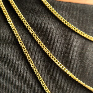 May include: Three gold-colored curb chains are displayed, each featuring a classic interlocking link design. The chains are arranged in parallel lines, and the text 1.5MM is clearly visible in the bottom left corner, indicating the width of the links.