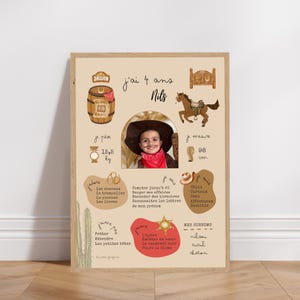 Peut inclure: Une affiche encadrée sur le thème du cow-boy. L'affiche présente une photo d'un enfant avec un chapeau de cow-boy et un bandana, ainsi que des illustrations d'un cheval, d'un saloon et du texte en français. L'enfant pèse 15,5 kg et mesure 98 cm.