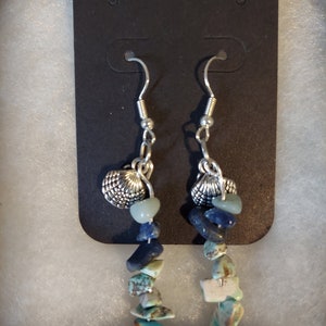 May include: A pair of dangle earrings with a silver seashell charm and blue and green gemstone beads.