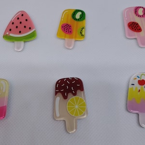 May include: Six colorful popsicle-shaped resin charms with various fruit and dessert designs. The charms feature watermelon, kiwi, strawberry, lemon, chocolate, and cherry designs.