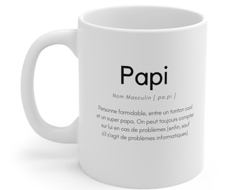 May include: White ceramic mug with the word "Papi" in black, along with a definition in French. The mug has a curved handle and a smooth surface.