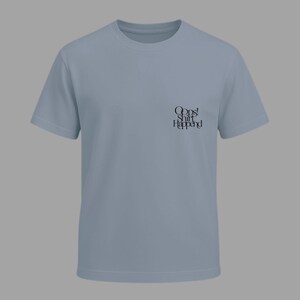 May include: A light blue t-shirt with short sleeves. The shirt has the text "Oops! Shit Happened" printed in black on the front. The shirt is made of a soft material and has a crew neck.