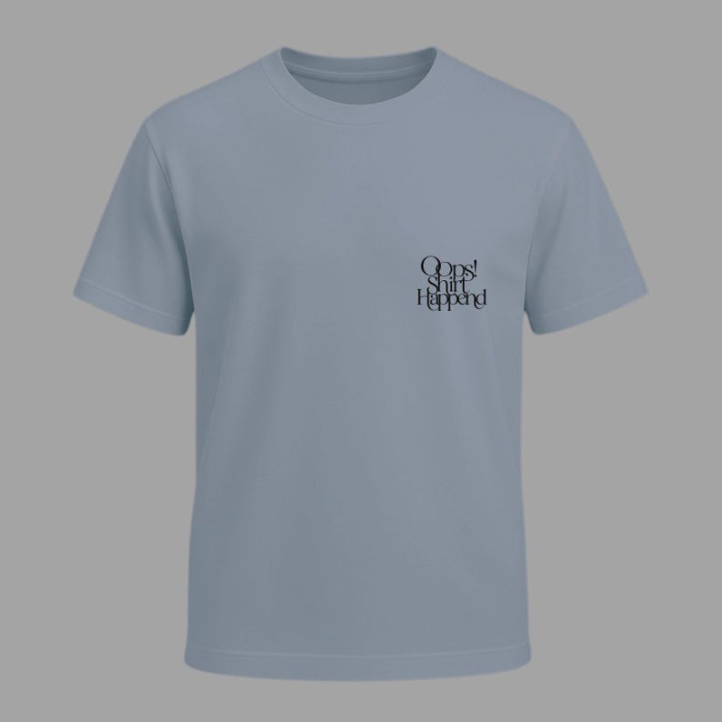 May include: A light blue t-shirt with short sleeves. The shirt has the text "Oops! Shit Happened" printed in black on the front. The shirt is made of a soft material and has a crew neck.
