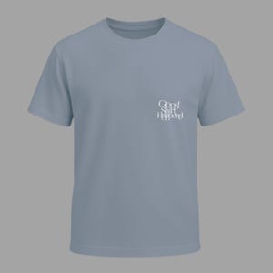 May include: A light blue t-shirt with short sleeves. The shirt features the text "Oops! Shirt Happened" in white script on the upper left chest area. The shirt is made of a soft material and has a crew neck.