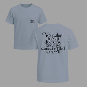 May include: Two light blue t-shirts. One shirt has the text "Oops! Shit Happens!" on the front. The other shirt has the text "You value doesn't decrease because someone failed to see it" on the back.