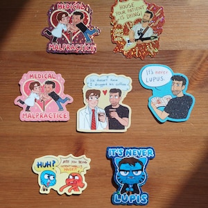 Puede incluir: Una taza de cerámica blanca con un asa negra y el texto "But First, Coffee" en negrita negra. La taza se encuentra sobre un fondo borroso, sugiriendo un ambiente acogedor.