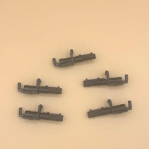 May include: Five black plastic toy machine guns. The guns have a barrel with multiple cylinders and a handle.