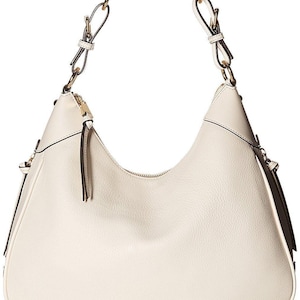 May include: Cream-colored hobo bag with a curved silhouette. Features a gold-tone chain strap and zipper closure. The bag has a subtle texture and the Calvin Klein logo in gold lettering.