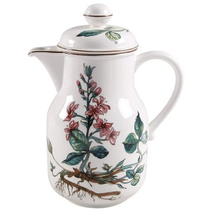 May include: White ceramic pitcher with a floral design featuring pink flowers and green leaves. The pitcher has a lid with a brown trim.