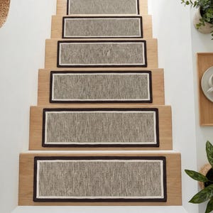 May include: A set of six rectangular stair treads. Each tread has a textured, light gray center with a dark brown border and a thin white inner border. The treads are installed on wooden stairs.