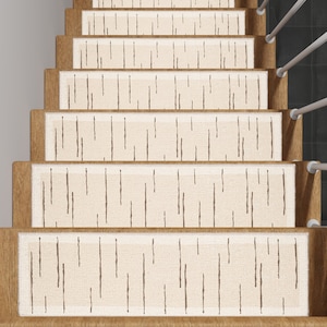 May include: Stair treads with a cream-colored, textured surface and a pattern of vertical brown lines. The treads are installed on wooden stairs. A white handrail is visible on the right side of the stairs.