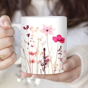 Puede incluir: Taza de cerámica blanca con un diseño floral con flores prensadas rosas y blancas. Las flores están dispuestas en un patrón de ramo en la taza.