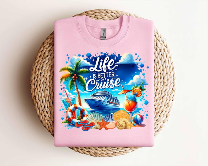 以下が含まれることがあります： クルーズ船、ヤシの木、カクテル、そして「Life is better on a cruise」というテキストが描かれたカラフルなグラフィックデザインのピンクのTシャツです。