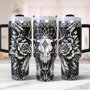 May include: Three black and silver stainless steel travel mugs with a black and white design featuring a bull skull, feathers, and flowers.