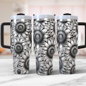 May include: Three stainless steel tumblers with black lids and handles. Each tumbler features a black and white sunflower design.