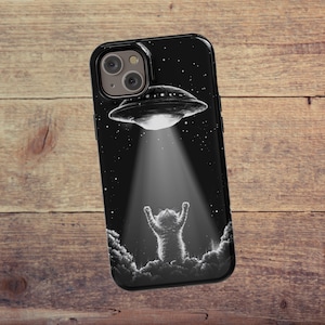 May include: Black phone case with a graphic of a cat looking up at a UFO with a beam of light shining down on it.