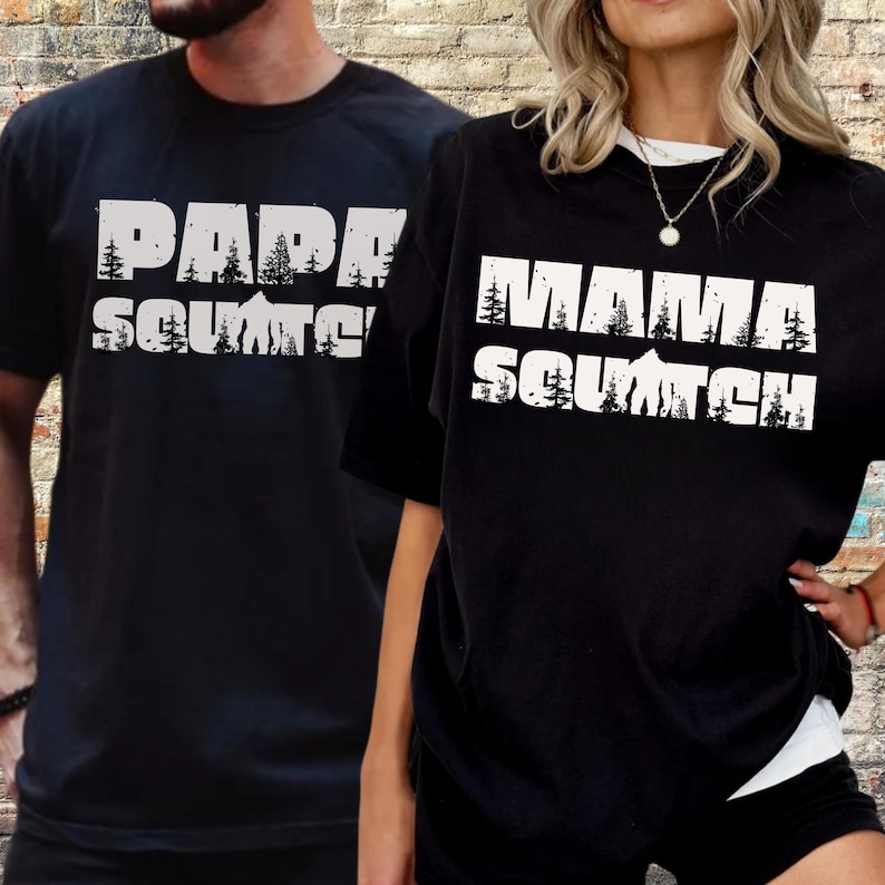 May include: Two black t-shirts with white text. The shirt on the left says "Papa Squatch" and the shirt on the right says "Mama Squatch".