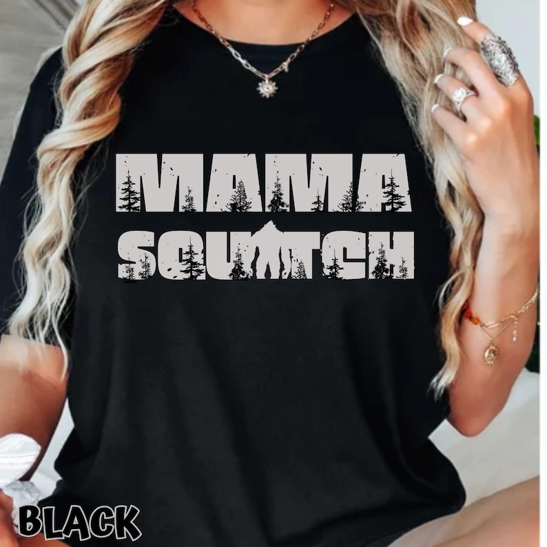 May include: Black t-shirt with a white graphic that says "Mama Squatch" with a silhouette of Bigfoot and trees.