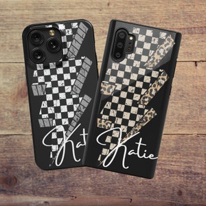 May include: Two black phone cases with a checkered flag design and the name "Katie" in white script. One case has a black and white checkered pattern, while the other features a black, white, and tan checkered pattern with a leopard print accent.