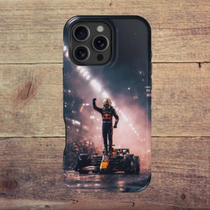 May include: Black phone case featuring a Formula 1 driver standing on a race car, raising a fist in victory. The case has a black border and a glossy finish. The background shows a crowd and stadium lights.