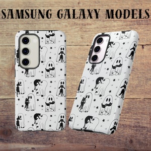 May include: Two white phone cases with a black and white ghost and cat pattern. The cases are for Samsung Galaxy models.