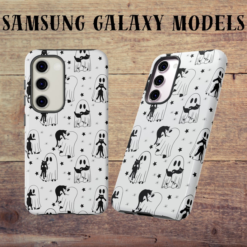 May include: Two white phone cases with a black and white ghost and cat pattern. The cases are for Samsung Galaxy models.