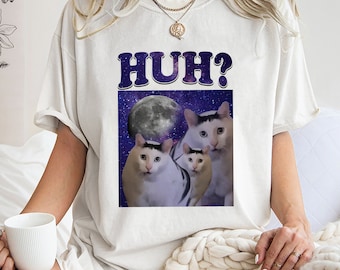 May include: White t-shirt with a graphic of three cats in space with a full moon. The text "HUH?" is printed in large, bold letters above the graphic.