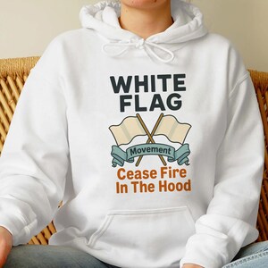 May include: White hooded sweatshirt with the text "WHITE FLAG" above an illustration of two crossed flags and the words "Movement" and "Cease Fire In The Hood". The sweatshirt is white.