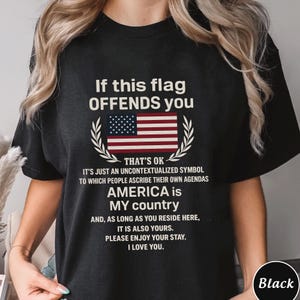 Op de afbeelding: Zwart T-shirt met de tekst "If this flag OFFENDS you" boven een Amerikaanse vlagafbeelding. Het shirt bevat de tekst "AMERICA is MY country" en andere gerelateerde tekst. Het shirt heeft een ronde hals.
