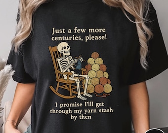May include: Black t-shirt featuring a skeleton knitting in a rocking chair, with a pile of yarn balls. Text reads "Just a few more centuries, please!" and "I promise I'll get through my yarn stash by then."