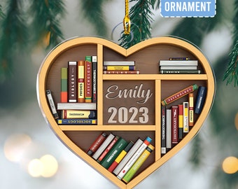 May include: A heart-shaped wooden ornament with a bookshelf design. The shelves are filled with books with titles like "Biology", "Physics", and "Thermodynamics". The ornament is personalized with the name "Emily" and the year "2023".