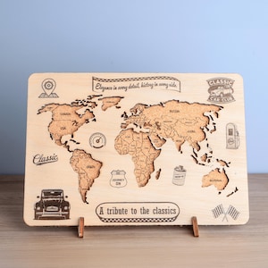 May include: A wooden world map with engraved continents and countries, featuring classic car-themed illustrations and text. The map includes the phrases "Classic Car Club" and "A tribute to the classics."