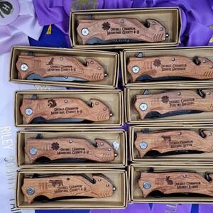 May include: Ten wooden boxes with engraved pocket knives. Each knife has a different inscription, including "Overall Champion" and "Senior Showman".