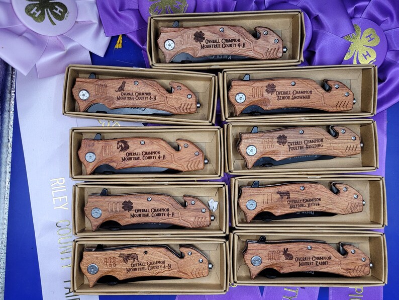 May include: Ten wooden boxes with engraved pocket knives. Each knife has a different inscription, including "Overall Champion" and "Senior Showman".