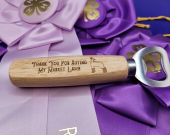 May include: Wooden bottle opener with a laser engraved lamb and the text "Thank You For Buying My Market Lamb". The bottle opener is resting on purple and pink ribbons.