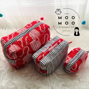 May include: Three red and white striped zippered pouches with the text "The Moo Moo & Mommy Co. Est. 2023" in a circle.