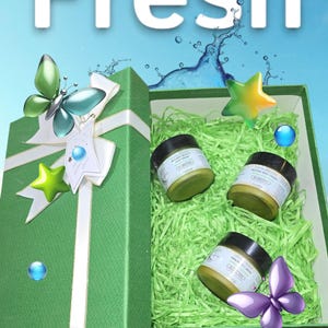 May include: A green gift box with a white ribbon and a bow. The box is open and contains three jars of body cream. The jars are labeled with the text "Natural Beauty Body Cream".