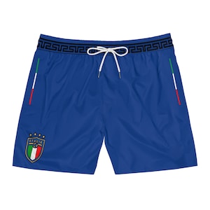 May include: Blue swim trunks with a white drawstring and a black and white Greek key pattern waistband. The trunks have a small Italian flag patch with the word "ITALIA" on the left leg.