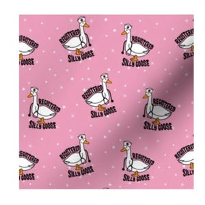 May include: A repeating pattern on a pink background featuring white geese wearing nurse caps and stethoscopes. Each goose is accompanied by the black text "REGISTERED SILLY GOOSE" and small white stars scattered throughout the fabric design.