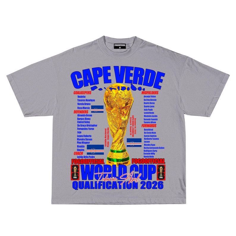 May include: Gray t-shirt with "CAPE VERDE" in blue and yellow lettering. Features a gold trophy graphic and text: "WORLD CUP QUALIFICATION 2026". Includes player names and team flags. A sports-themed tee.