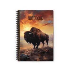 Op de afbeelding: Een bruine bizon staat in een veld met een zonsondergang op de achtergrond. De bizon kijkt naar de linkerkant van de afbeelding. De notebookhoes heeft het woord "NOTEBOOK" in het zwart bovenaan de afbeelding.